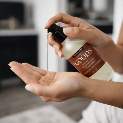 Person holding a bottle of 'The Goods' product over another hand with a blurred background
